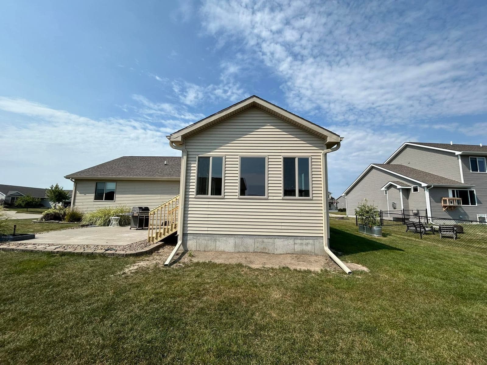 A finished single-story addition in tan siding with white trim and a row of new windows, joined to the main roofline.