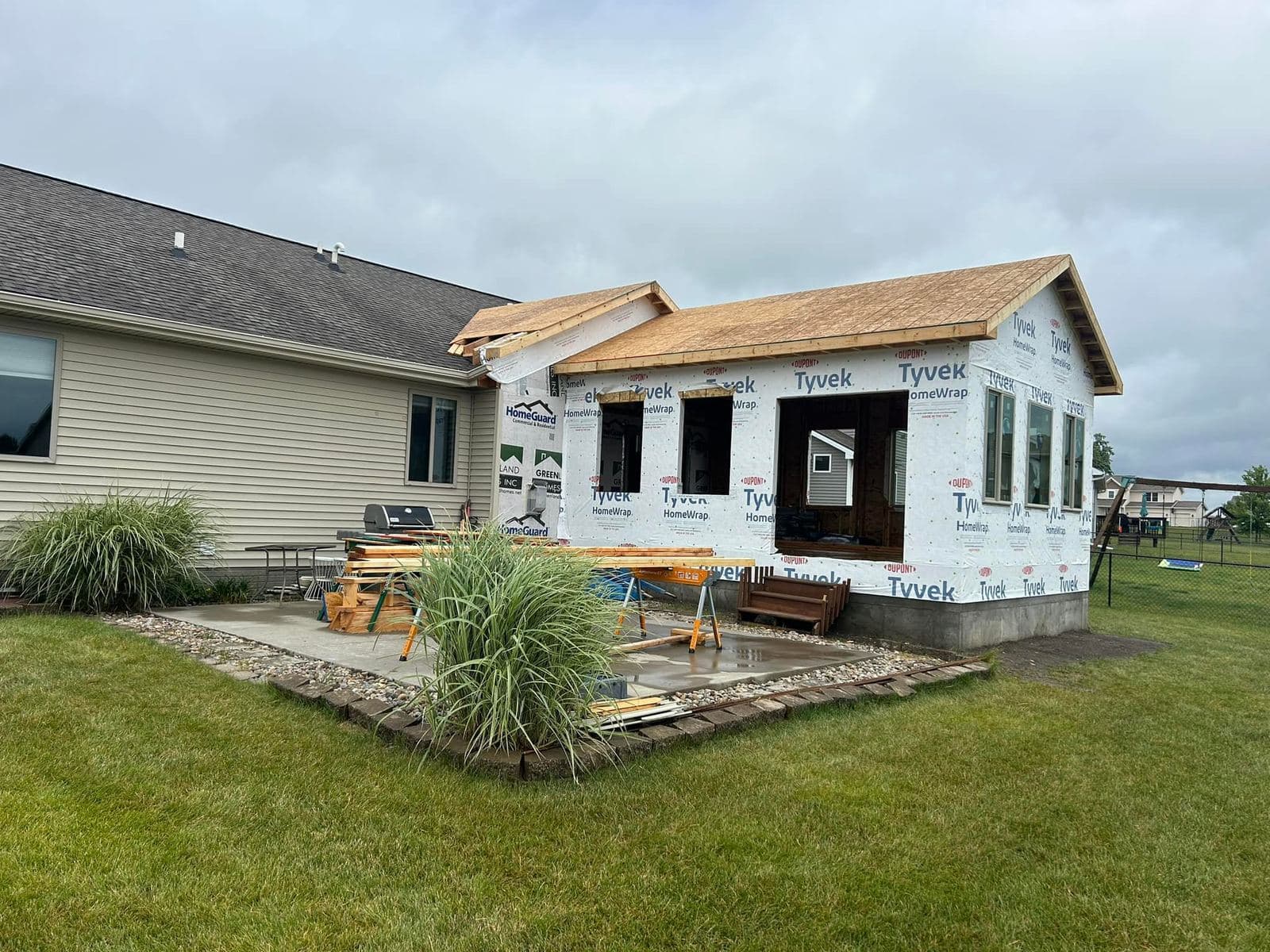 An addition framed and sheathed under weather-resistant wrap, with window openings cut and ready for units.