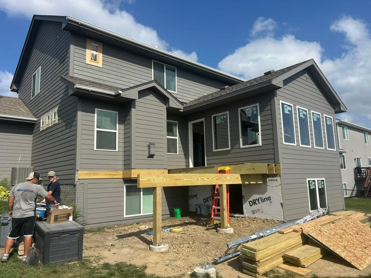 A two-story addition framed and sheathed, with the crew working from scaffolding