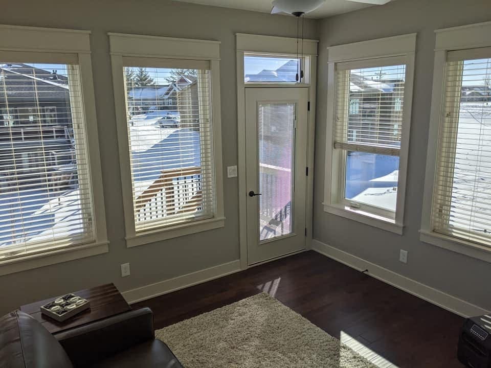 The inside of a finished sunroom addition, windows on three sides and a glazed door onto the deck.