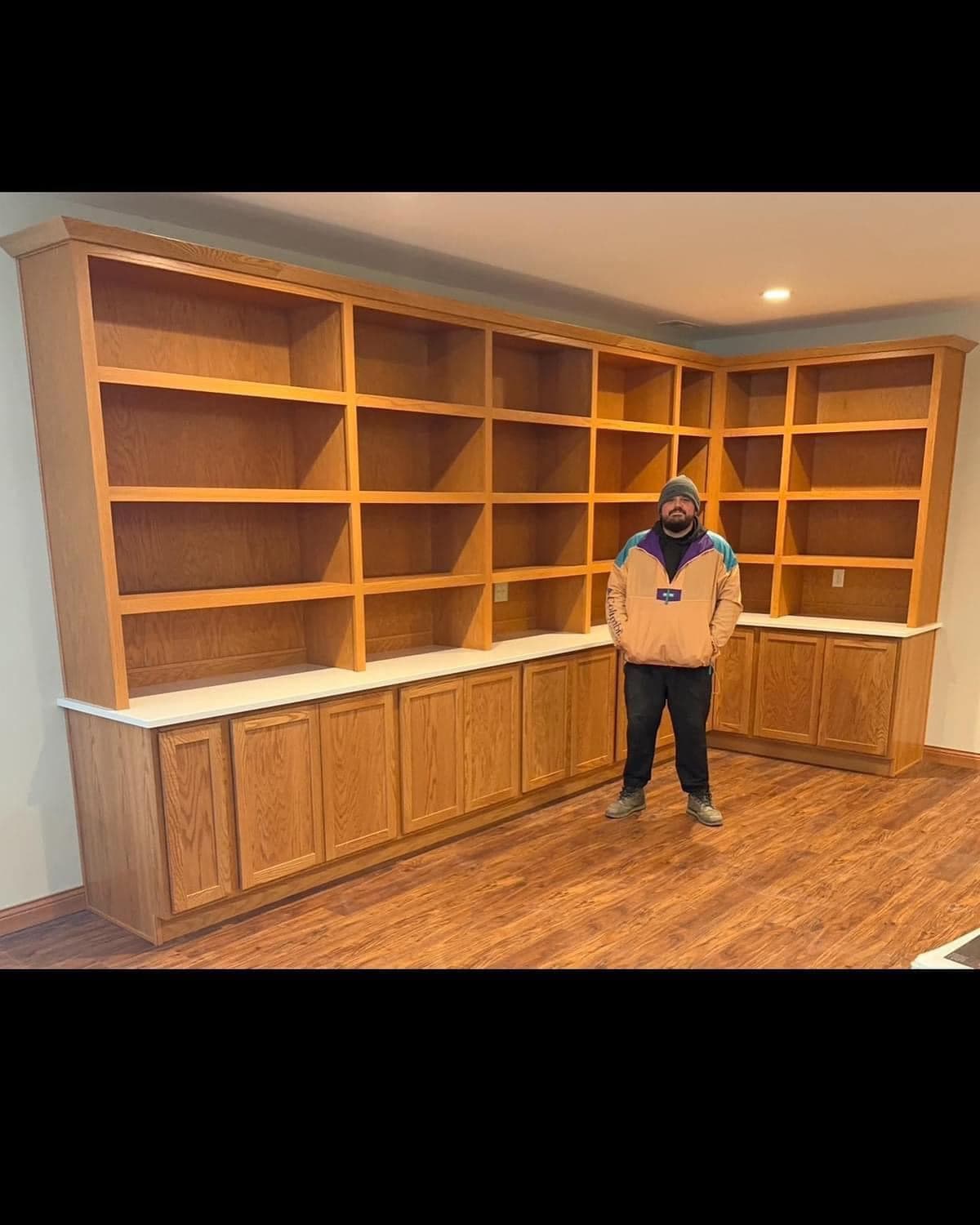 A custom built-in shelving wall spanning a finished room, built in stained oak with a continuous base cabinet run.