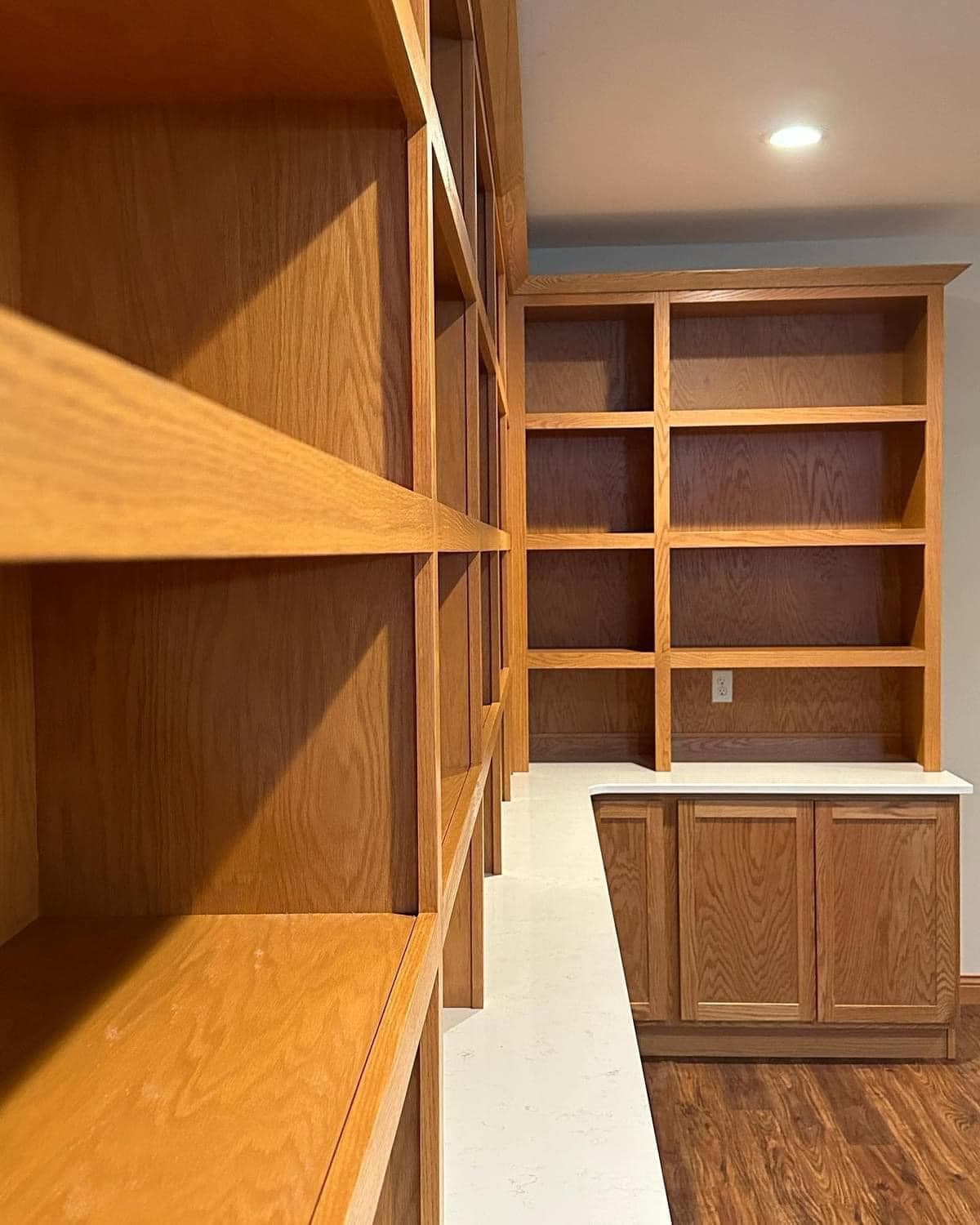 Custom oak pantry shelving with adjustable open bays above a run of lower cabinet doors.