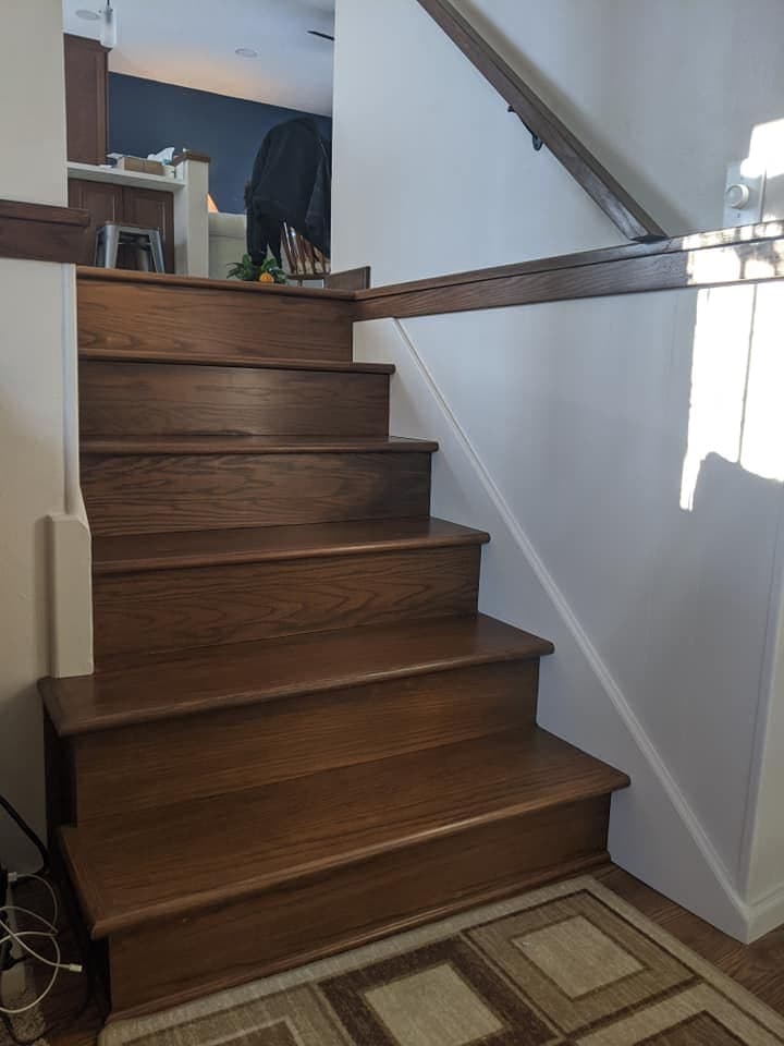 A staircase with oak treads, white risers and an oak handrail and cap.