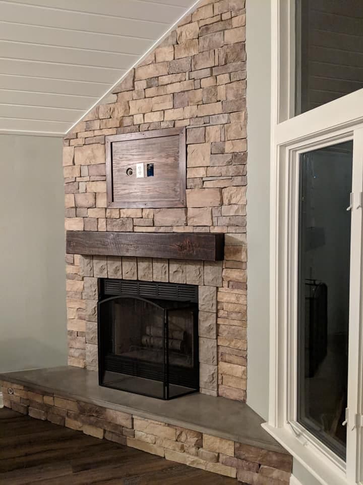 A stacked-stone fireplace with a custom timber mantel and hearth.