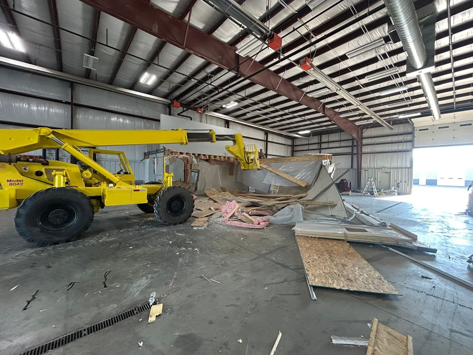 A telehandler working inside a commercial unit during a strip-out, with the old fit-out stacked on the floor.