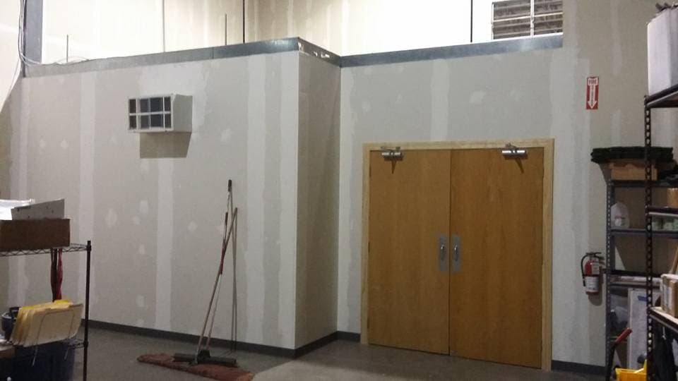 A commercial build-out with the drywall up and a pair of timber doors hung into a new partition.