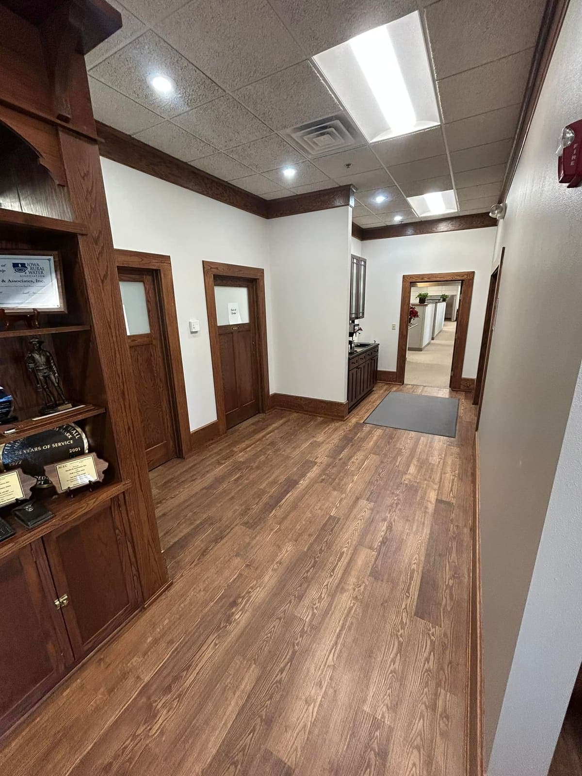 A finished office corridor with timber doors, a suspended ceiling and recessed lighting.