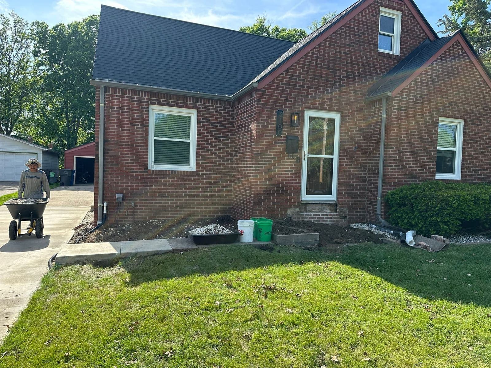 Fresh driveway flatwork run up to the side of a brick house, with the excavated ground waiting to be made good.