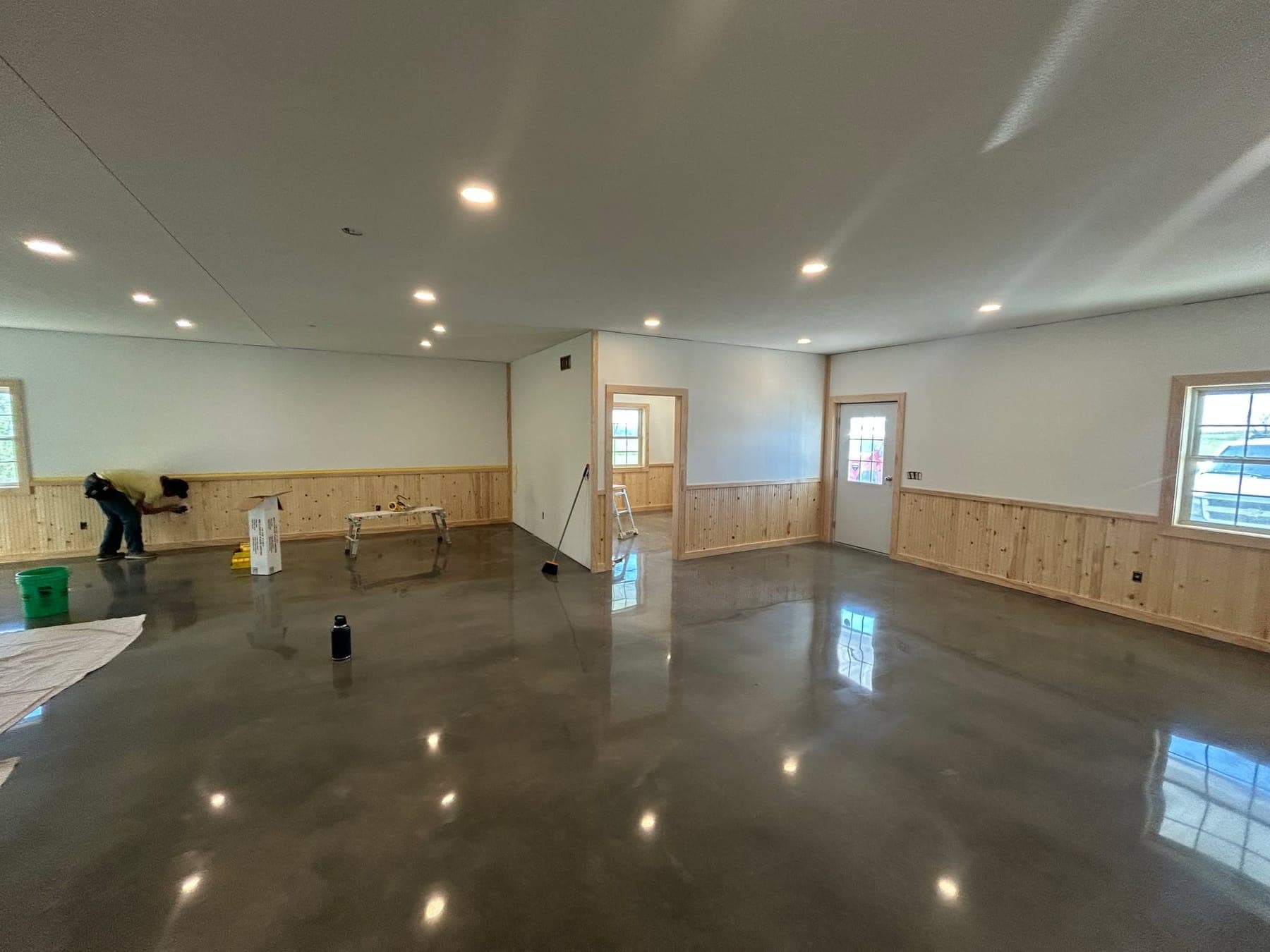 A polished and sealed concrete floor running the length of a finished shop, reflecting the lights above it.