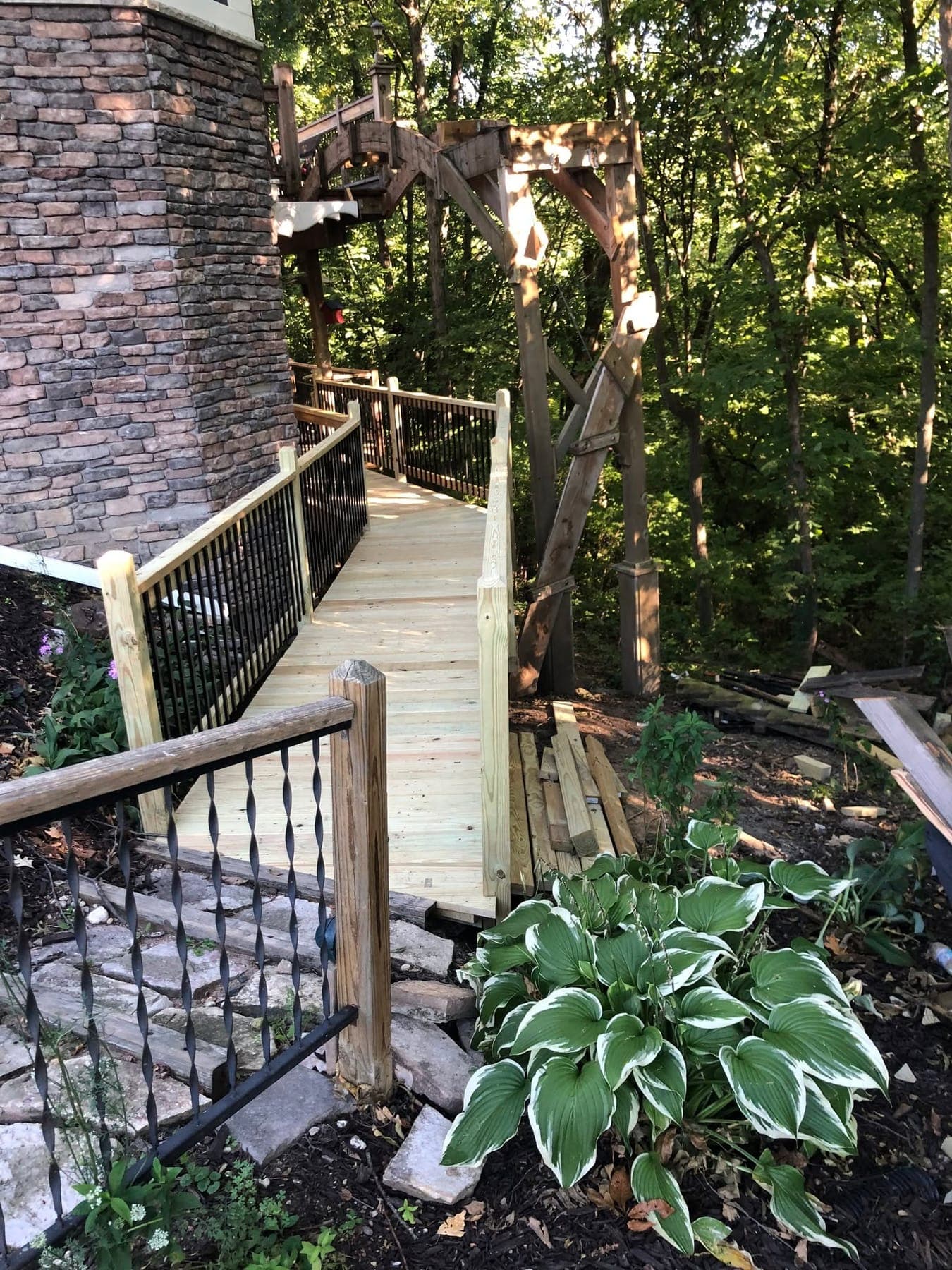 A raised timber walkway with black balusters running through trees