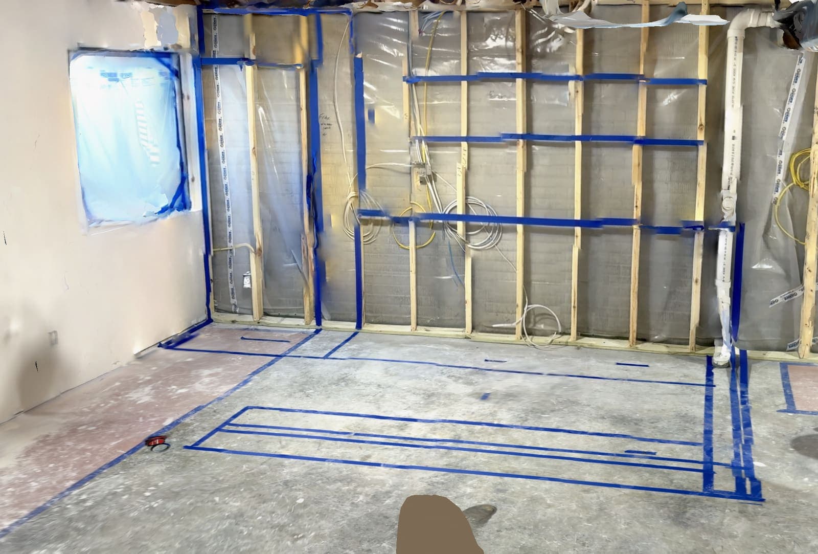 A basement bar laid out full size on the wall in blue tape before any cutting began.