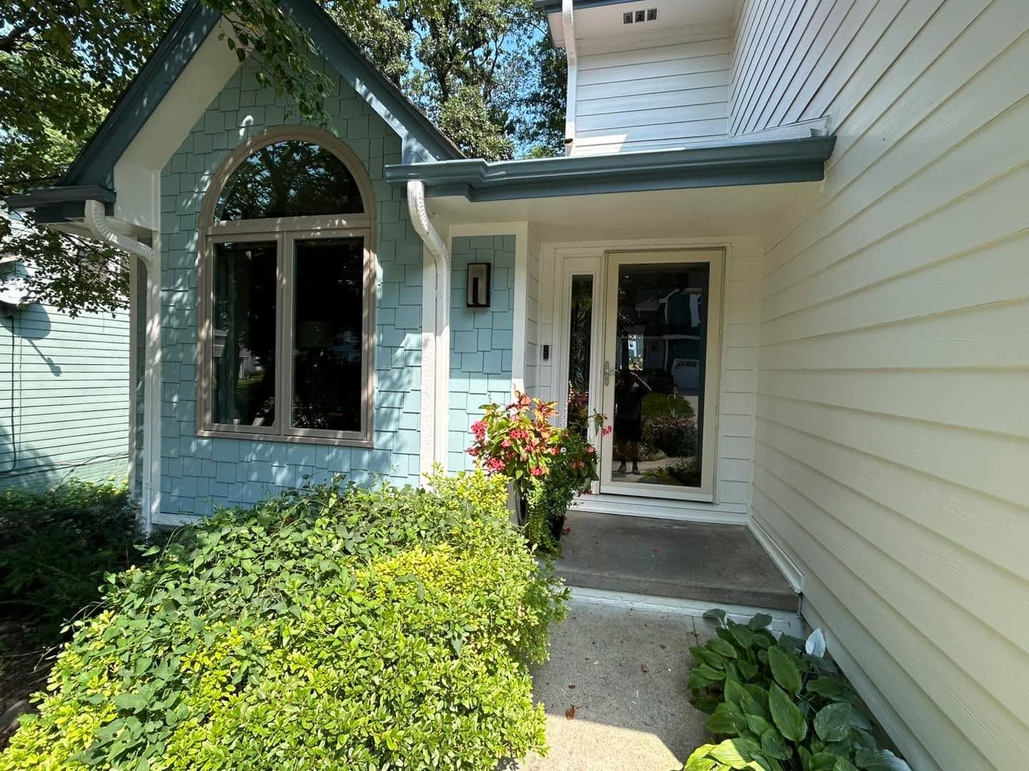 A front entry with an arched feature window above the door, framed by fresh white trim on pale blue siding.