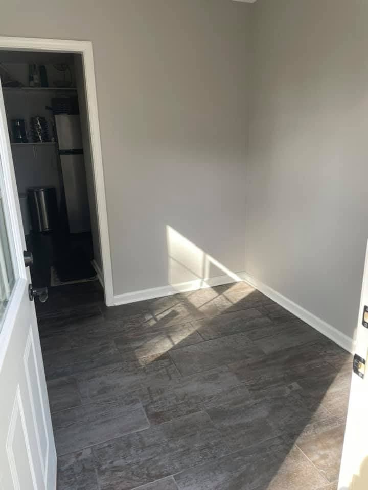 A finished room with smooth white drywall, clean inside corners and new baseboard over plank flooring.