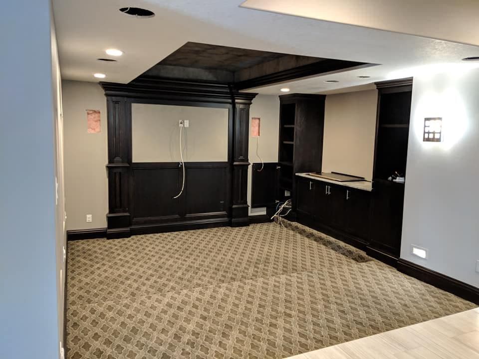 A finished basement with hung and textured drywall, recessed lighting and dark stained wall panelling.