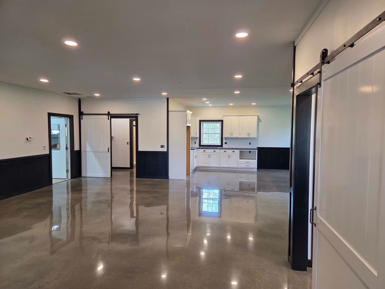 Recessed lighting and under-cabinet lights across a finished living space, looking through to the kitchen.