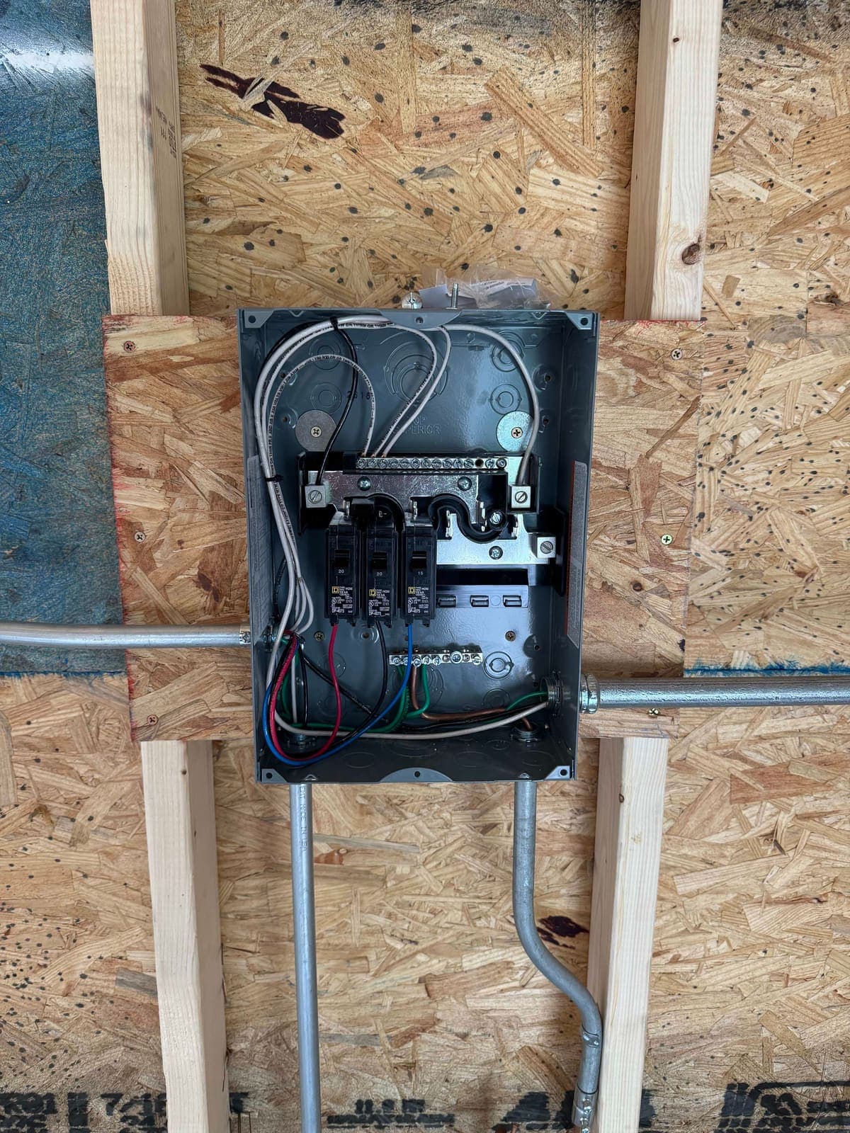 A sub-panel with its cover off, conduit fed in from above and every conductor landed neatly.