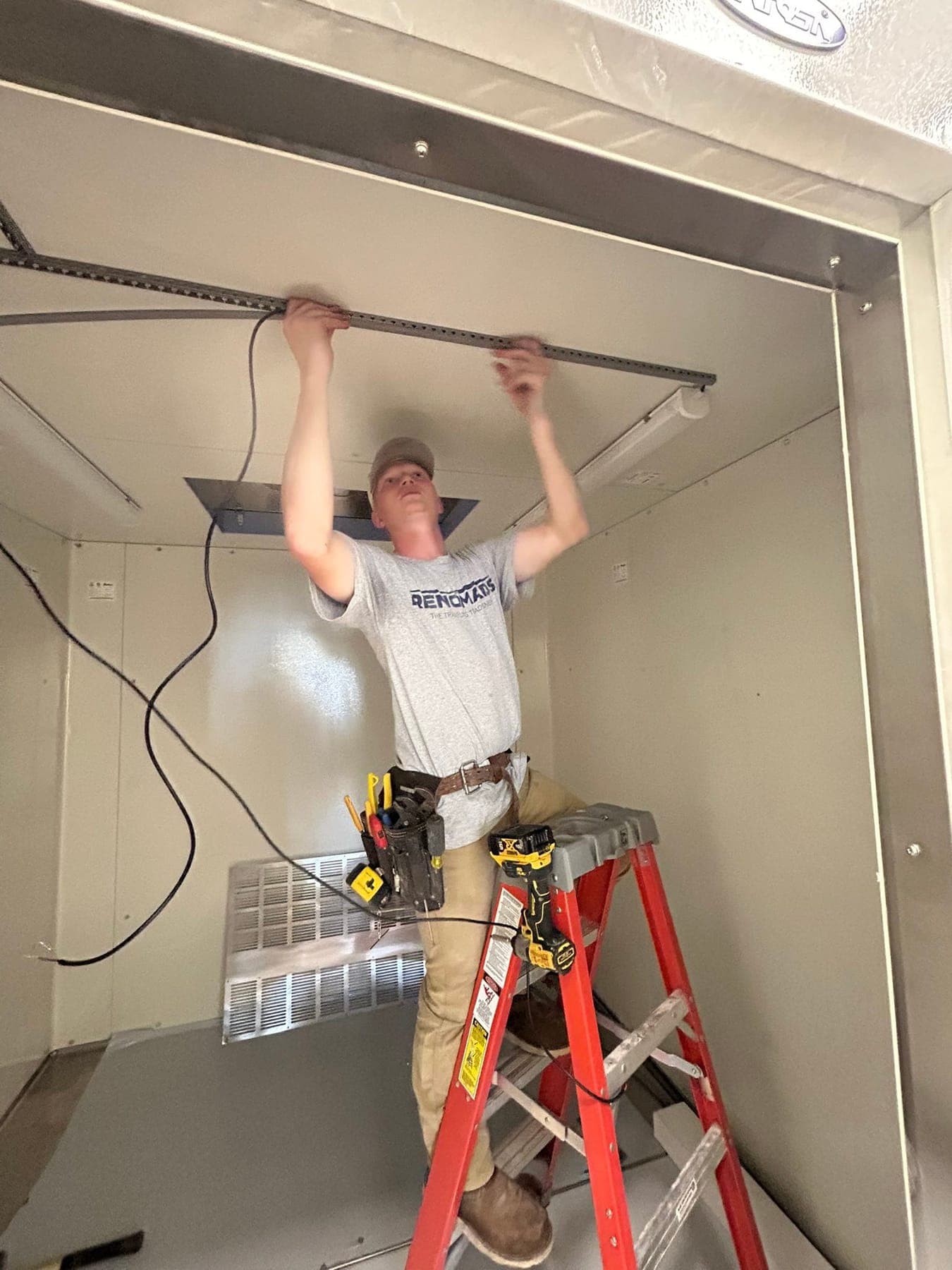 An electrician fitting a light into a ceiling recess