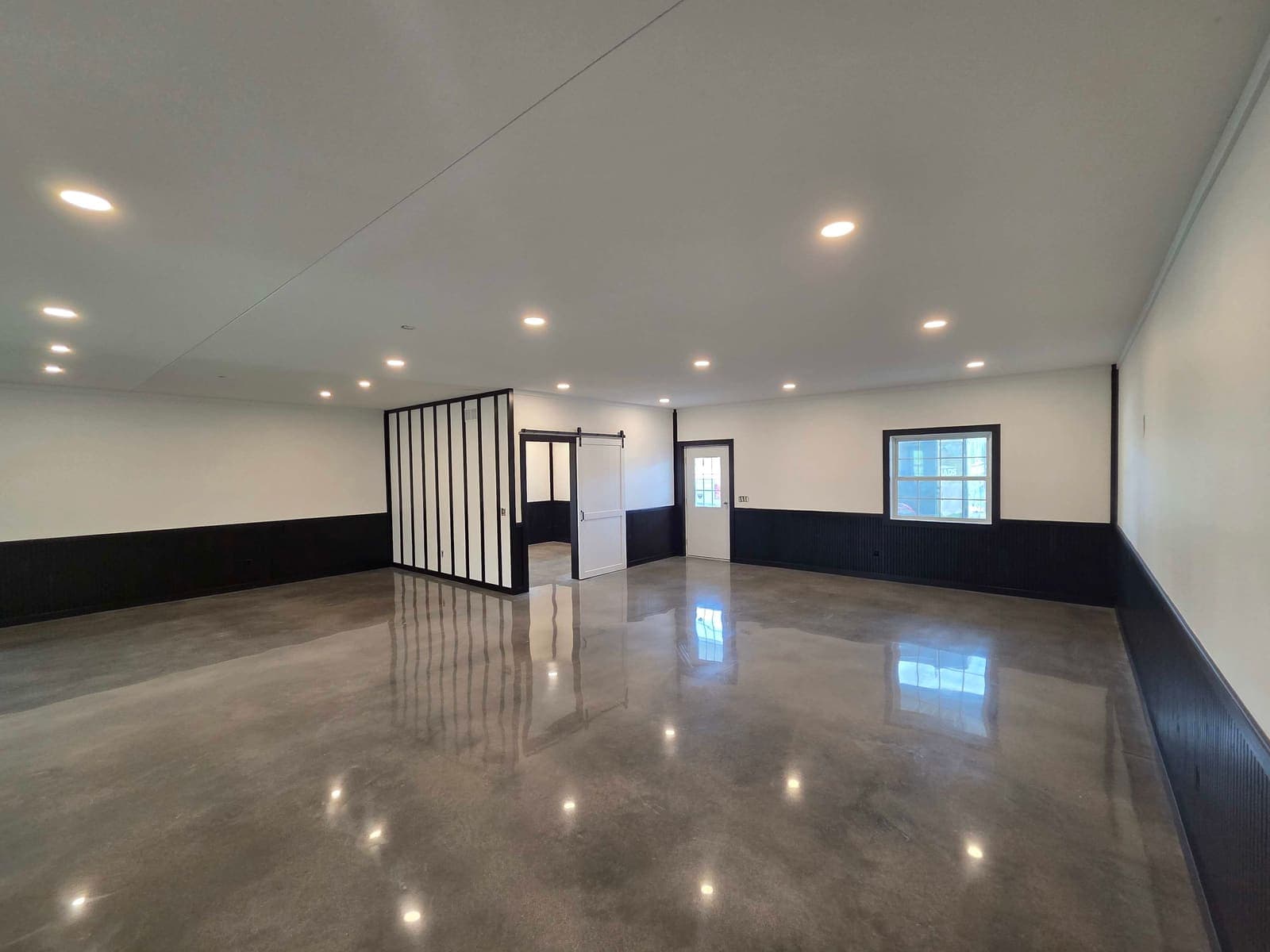 A finished open-plan room lit by rows of recessed ceiling lights over a polished concrete floor.