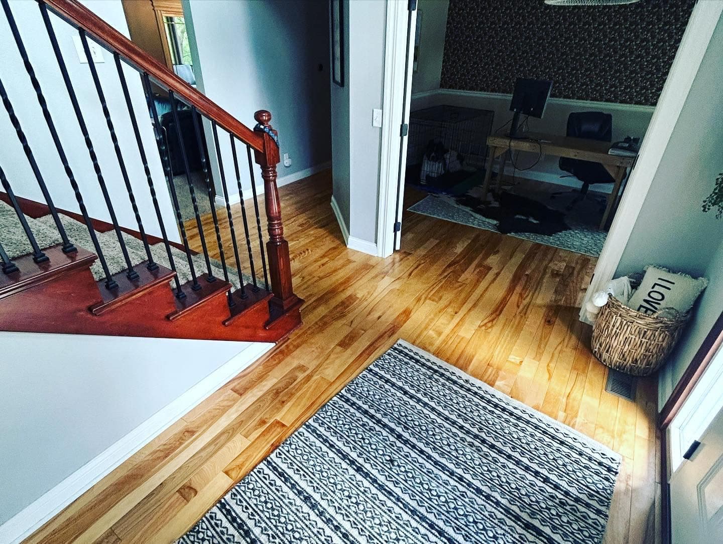 Hardwood flooring meeting a staircase with black metal balusters and a dark stained handrail.