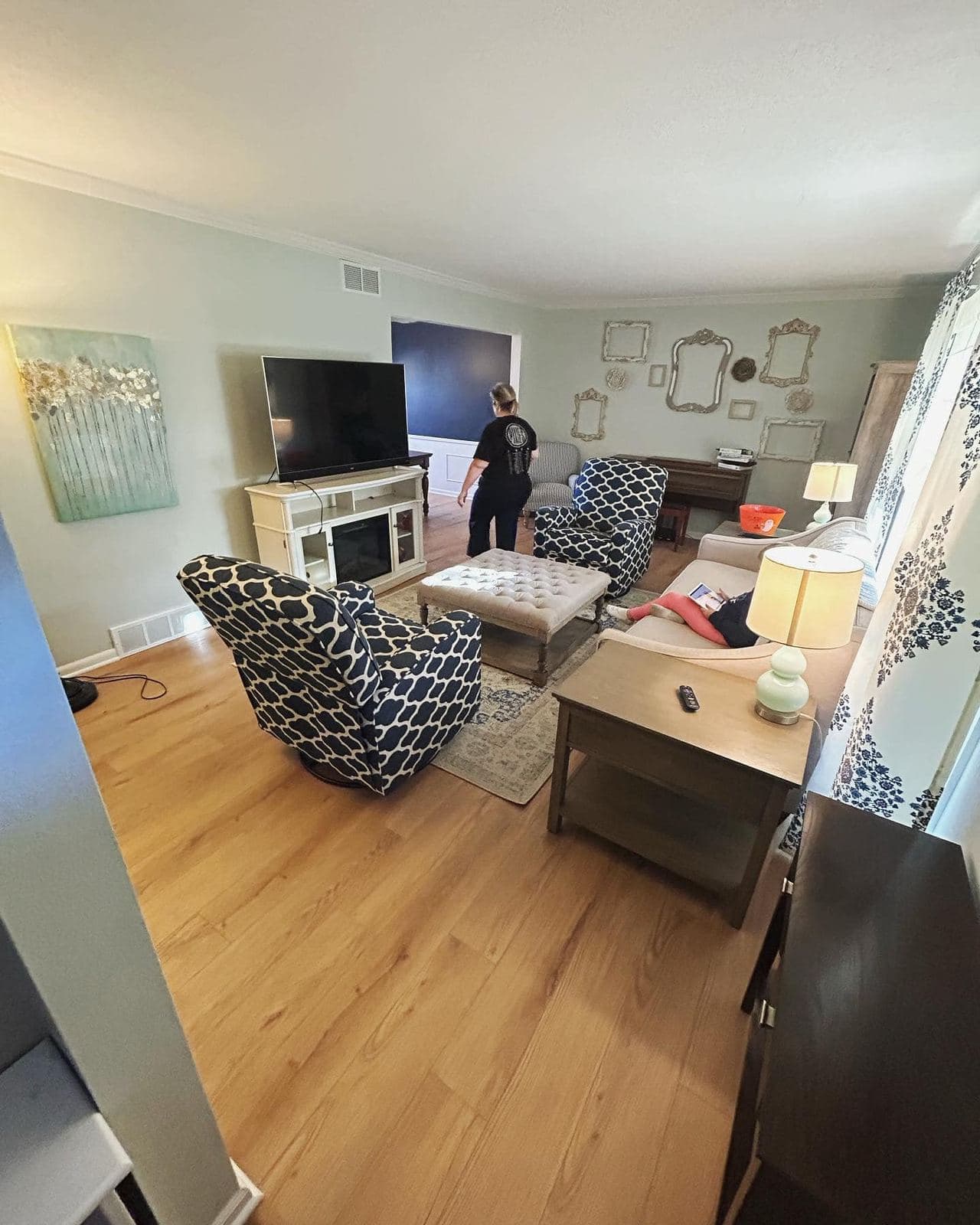 A finished living room with wood-look plank flooring, light walls and a wall-mounted television.