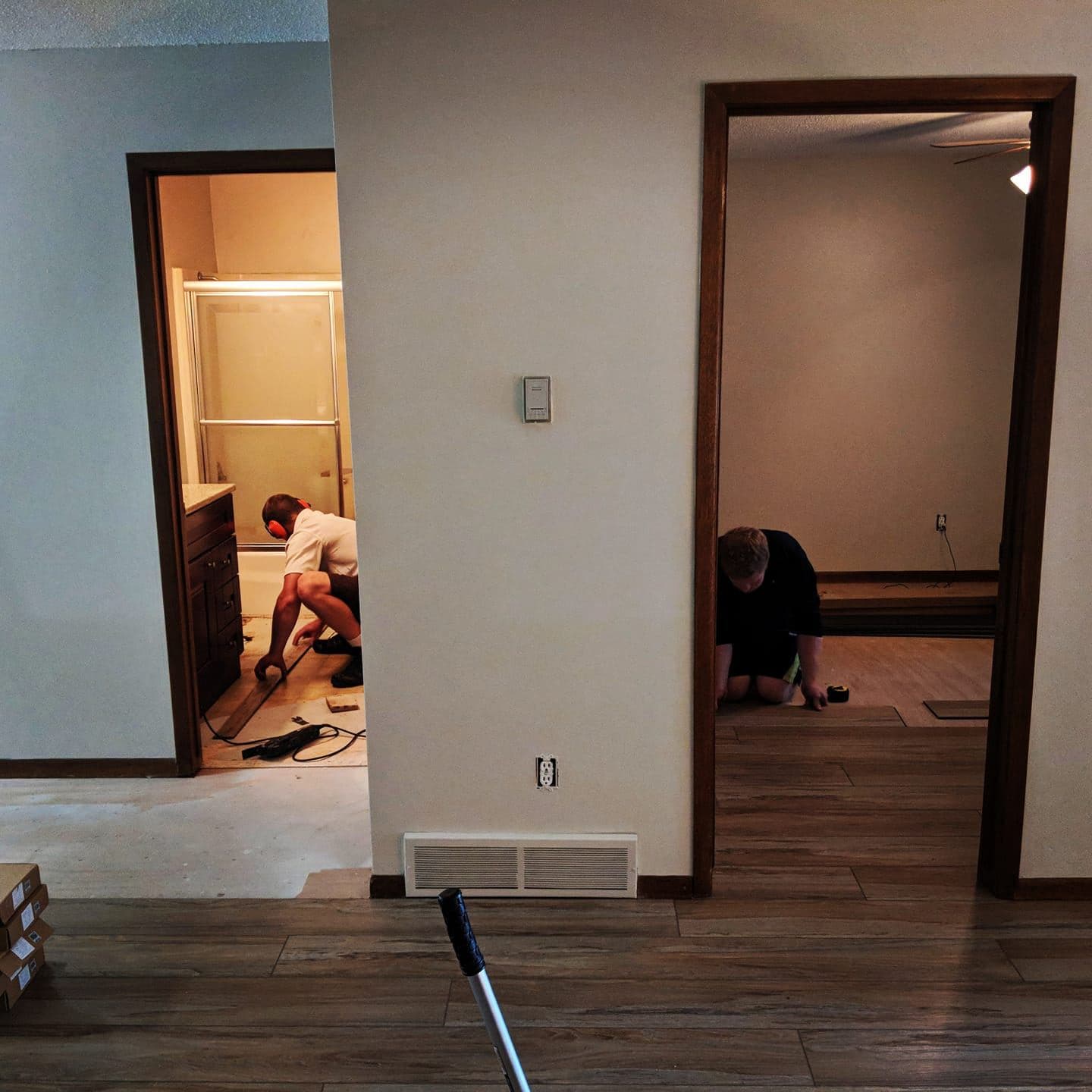 New plank flooring being laid through a hallway and into two adjoining rooms.