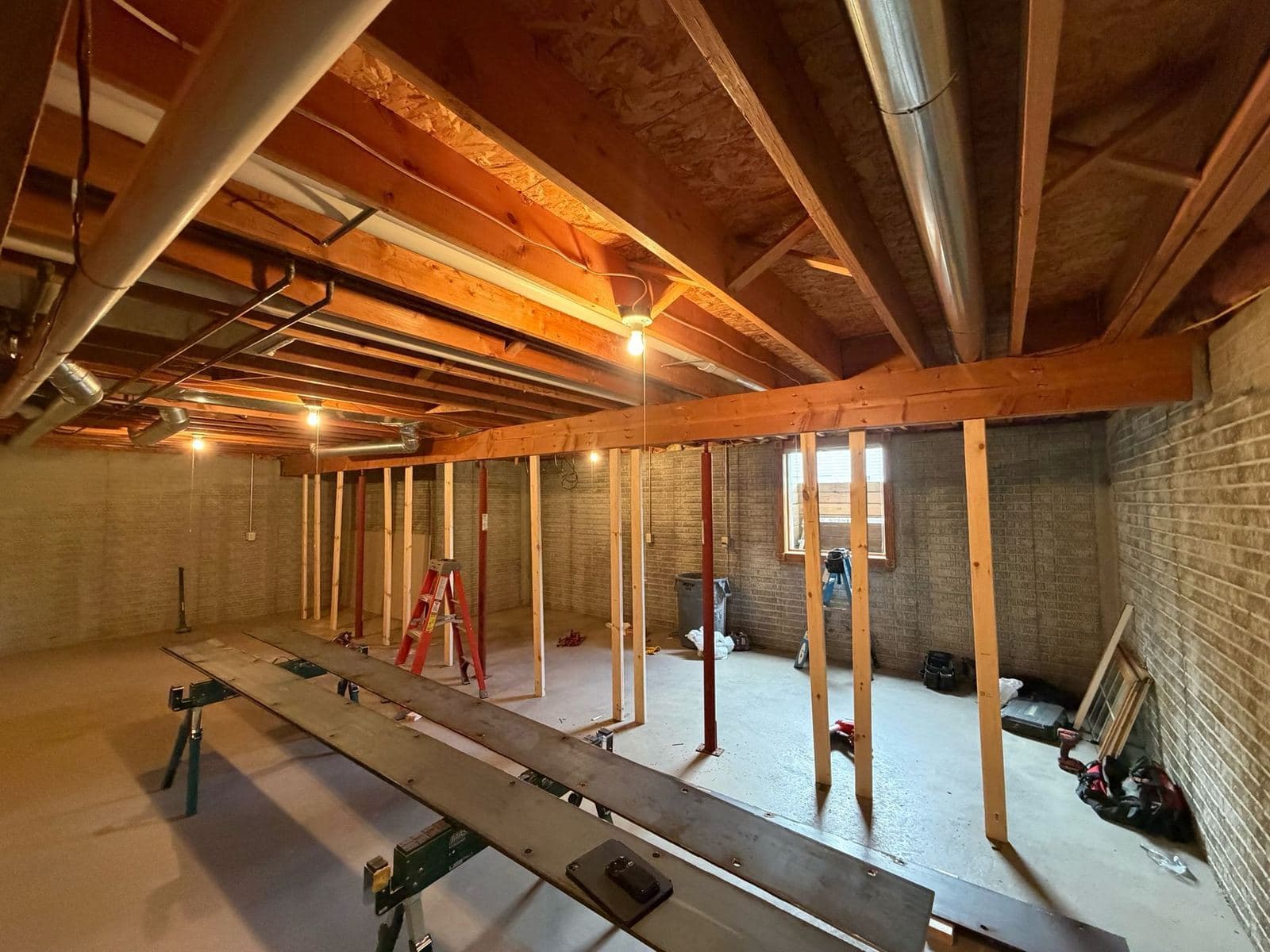 A basement being framed out, with a steel beam and support posts running the length of the space.
