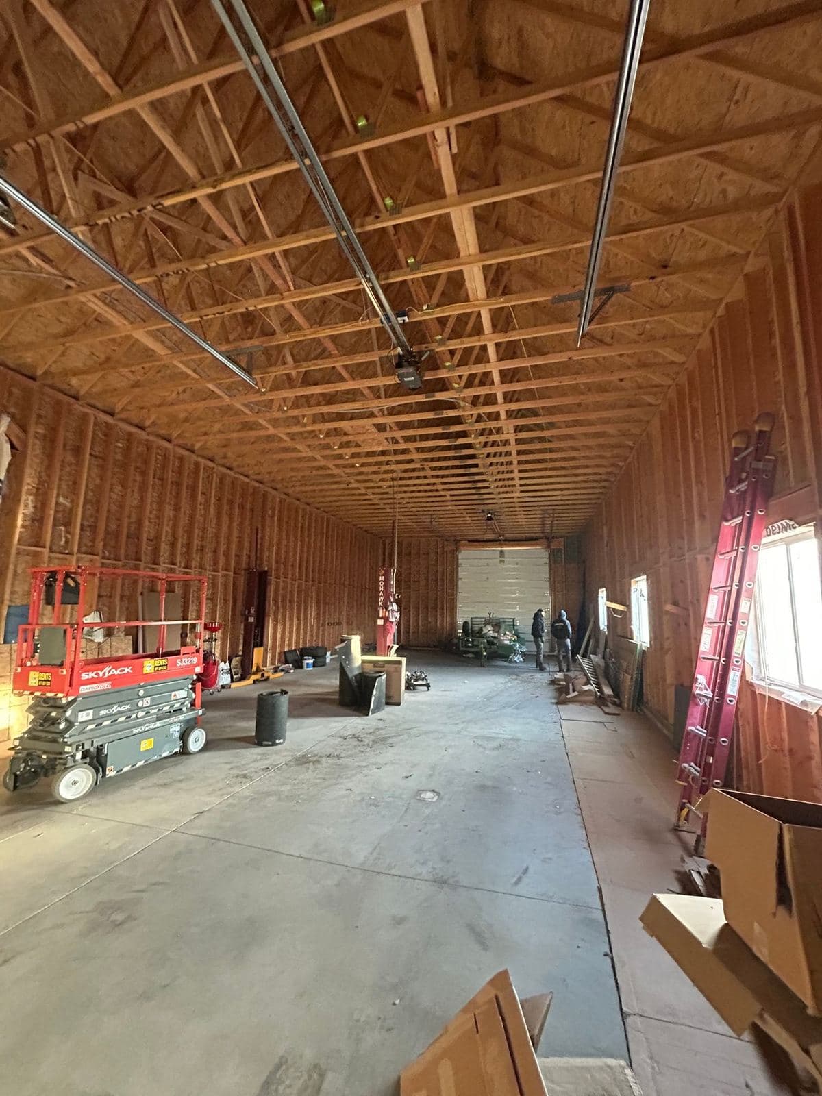 Garage framing seen along the wall line, with roof trusses and bracing above the open studs.