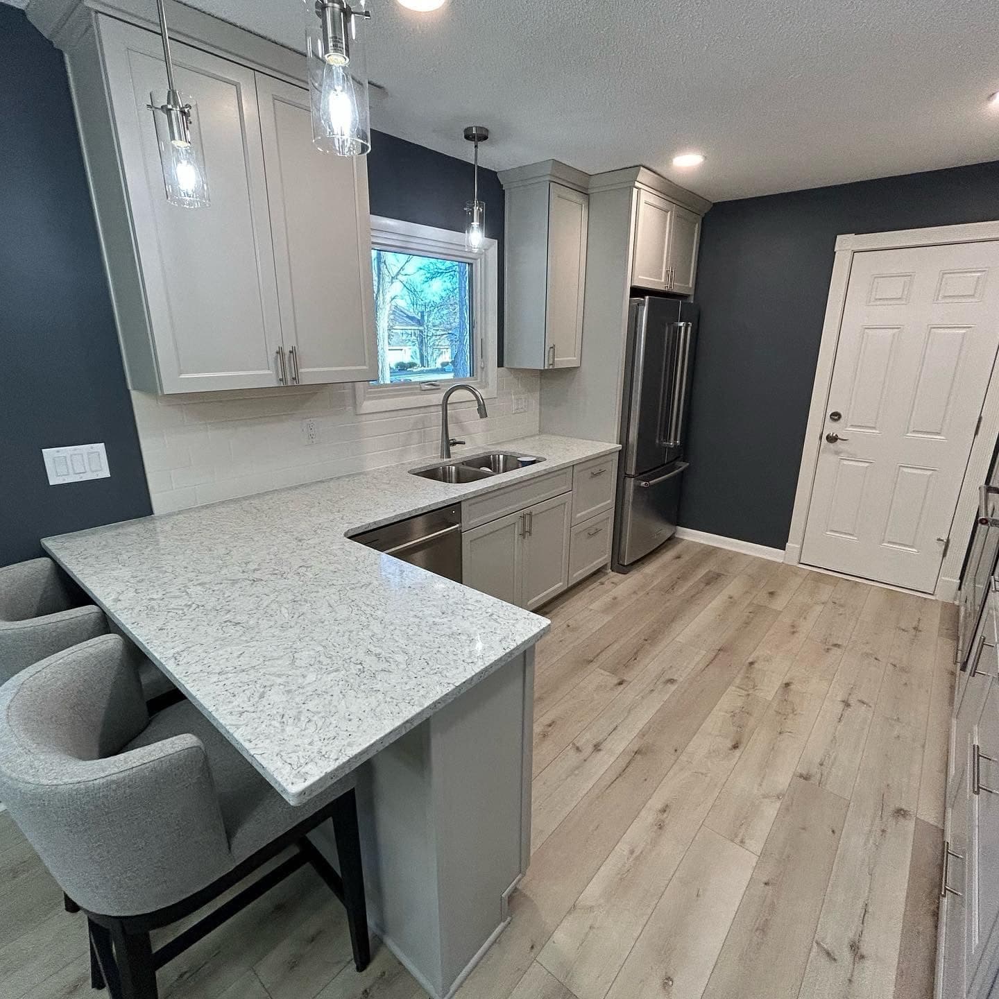 A kitchen with a quartz peninsula against a navy wall