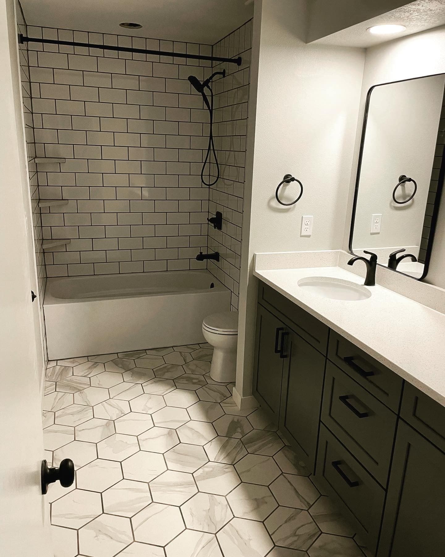 A bathroom with a subway-tiled tub surround and a hexagonal tile floor