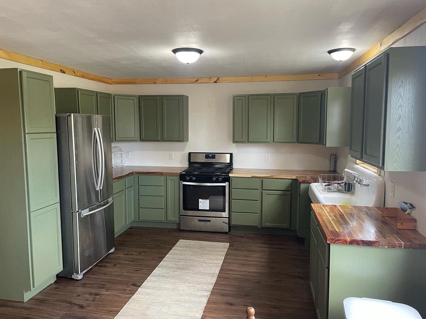 Kitchen cabinets repainted sage green with new hardware.