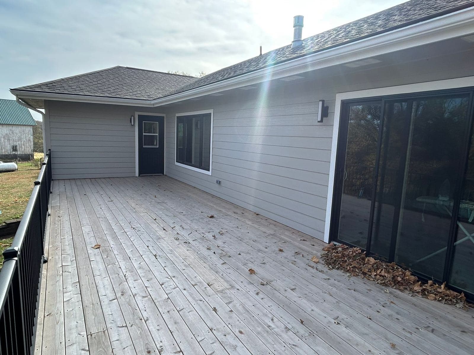 A long white-sided elevation with a weathered deck running its full length, sliding doors and a low-pitch roofline.