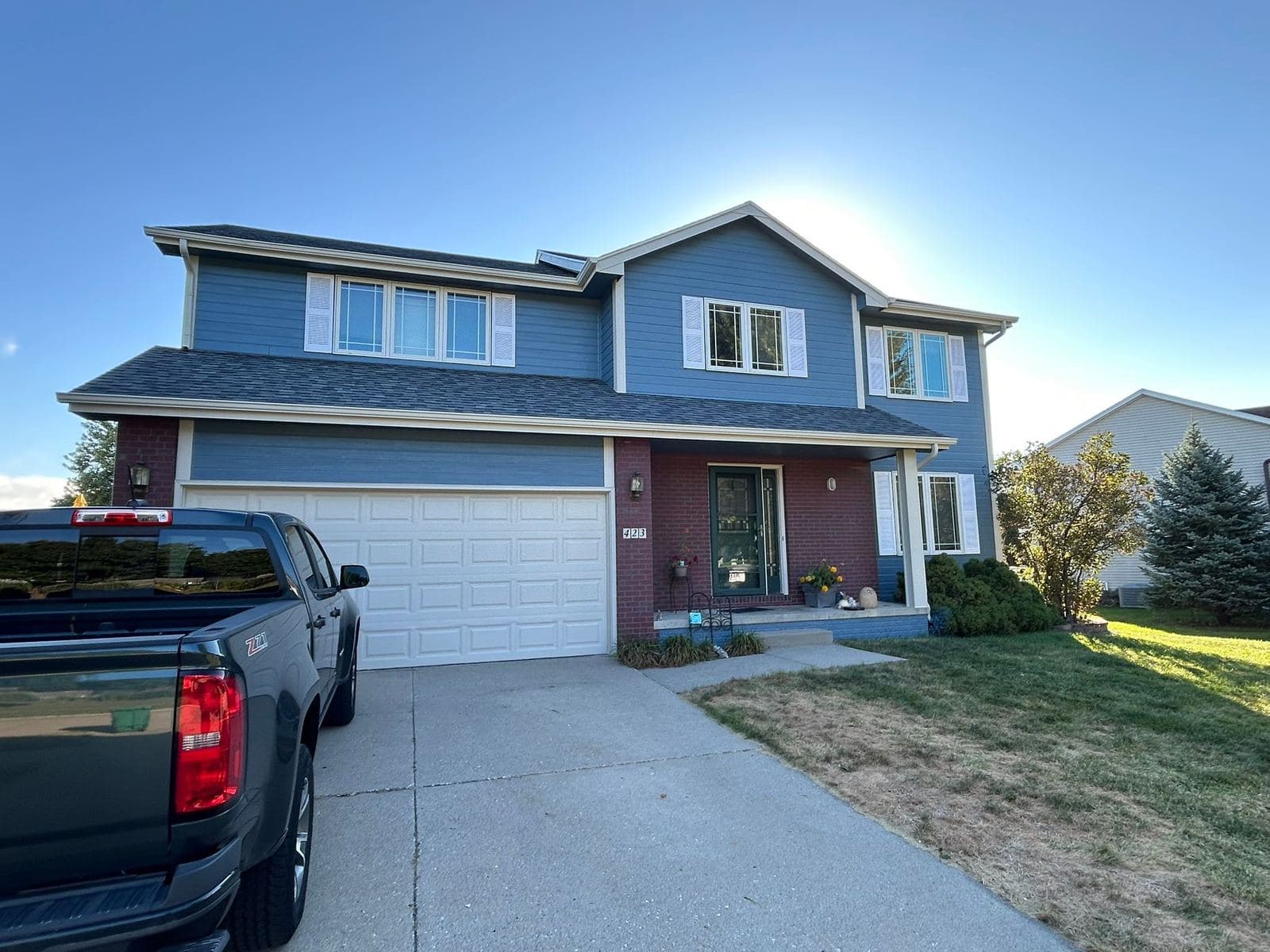 A two-story home in blue lap siding with white trim and a deep red front door, with an attached two-car garage.