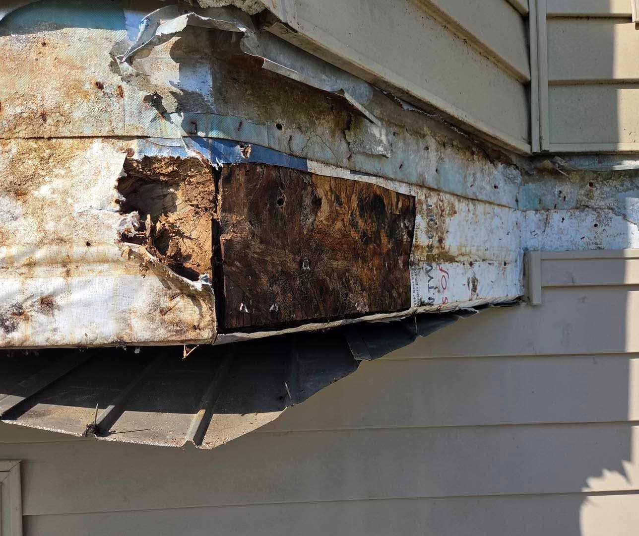 Siding peeled back from a cantilevered box-out to show the framing behind it rotted right through.